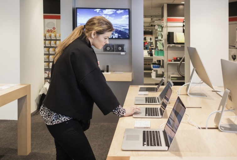 Laptopokat néz egy nő egy műszaki áruházban