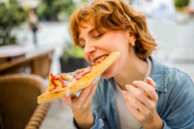 Fiatal nő eszik nagy áhítattal egy szelet pizzát