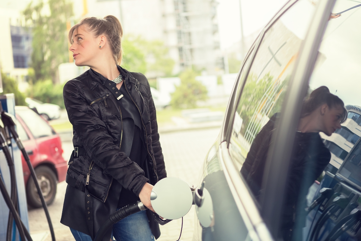 Fiatal nő tankolja az autóját