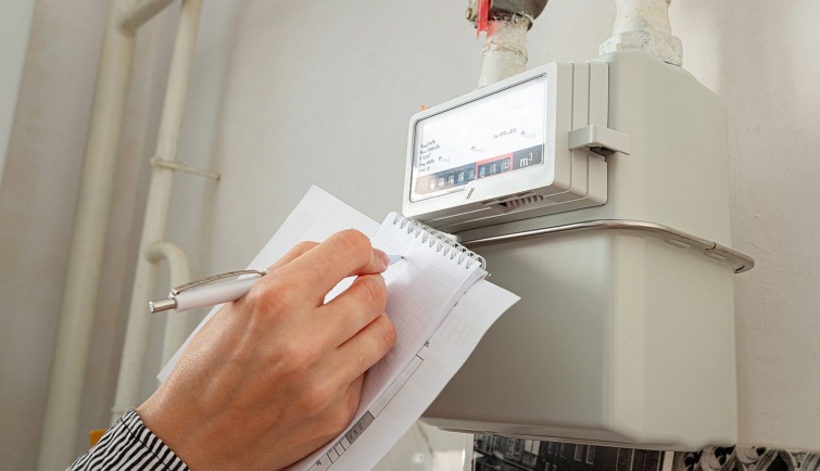 Egy kéz felírja egy füzetbe a gázóra állását.