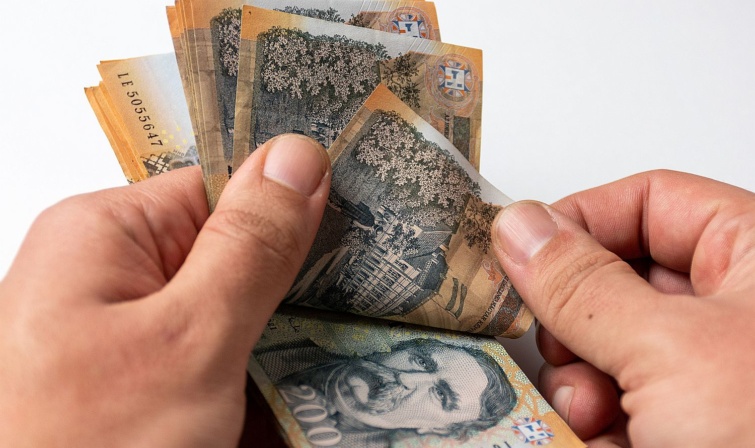 Húszezer forintos bankjegyeket számol egy kéz.