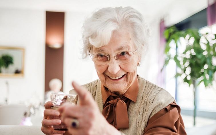 Nevető idős nő pohárral a kezében.