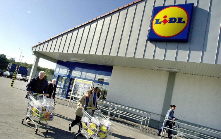 Vásárlók tolják a megpakolt bevásárlókocsijaikat a Lidl egyik üzlete előtt.