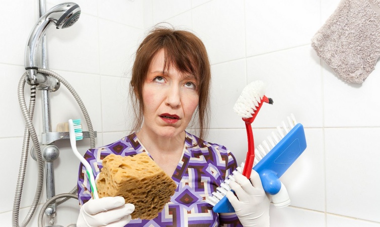 Egy mérges nő takarítóeszközökkel a zuhanyzóban.