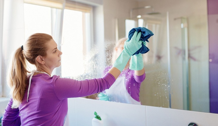 Egy nő egy tükröt takarít.