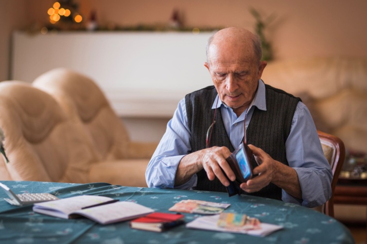 Egy nyugdíjas férfi számolja a pénzt, kiadásokat.