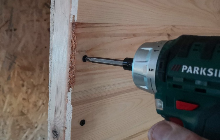 Egy Parkside márkájú csavarozóval behajtanak egy csavart a deszkába.