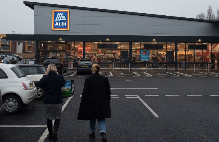 Vásárlók és autók egy Aldi üzlet parkolójában szürkületben