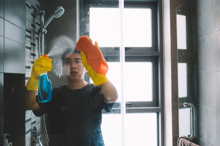 Férfi tisztítja a zuhanykabint.