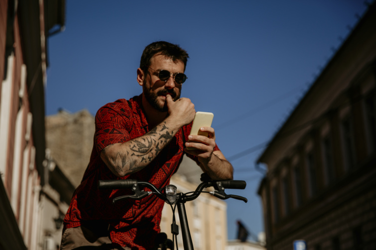 Tetkós csávó biciklin eltévedve kezében telefonnal térképet néz