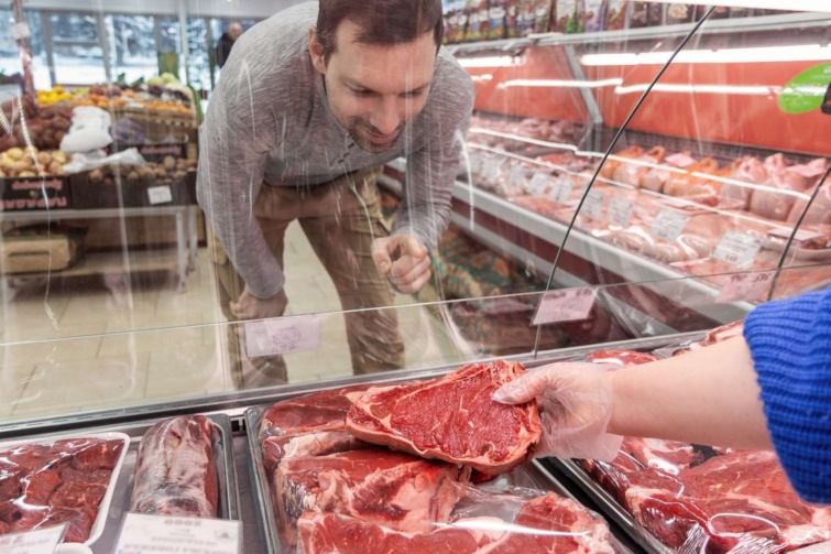 húspulttal szemező férfi kiválaszt egy szelet húst