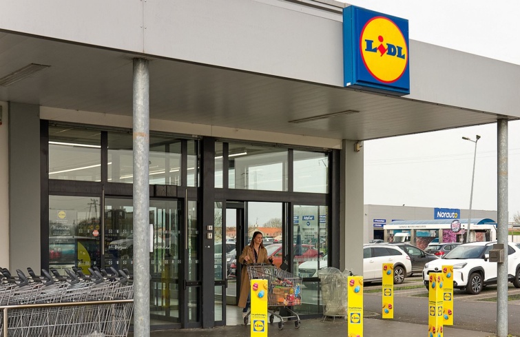 Egy nő vásárló bevásárlókocsival elhagy egy Lidl-üzletet.