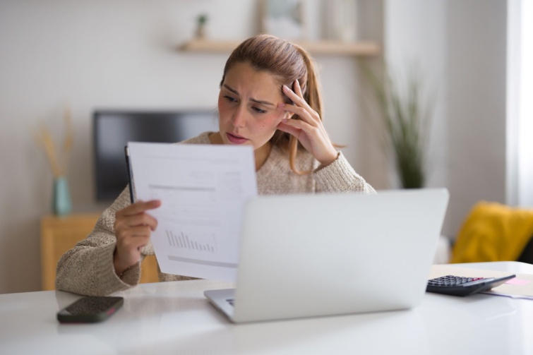 Fiatal nő aggódik a háztartási számlák miatt, ellenőrzi a pénzügyeit és problémái vannak a fizetésükkel