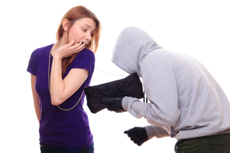 Egy csuklyás pulóveres férfi egy fiatal nő táskáját készül ellopni.