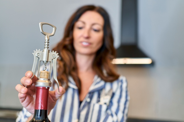 Nő parafadugót húz ki borosüvegből.