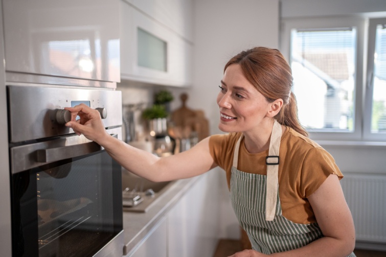 Mosolygó nő állítja be a sütőt.
