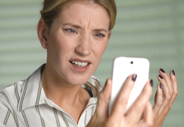 Egy fiatal néz megdöbbenve néz a kezében tartott fehér telefonra