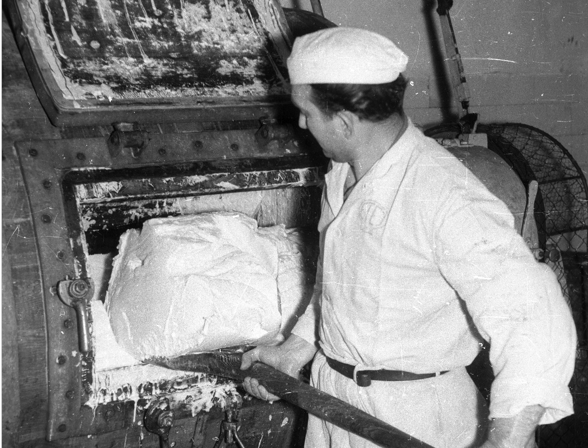 Egy férfi lapátolja a vajat egy vajköpülő gépben