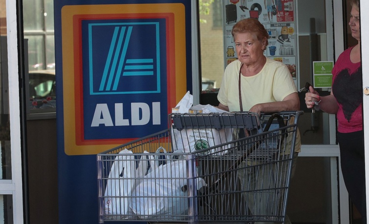 Egy idős nő bevásárlókocsival elhagy egy Aldit