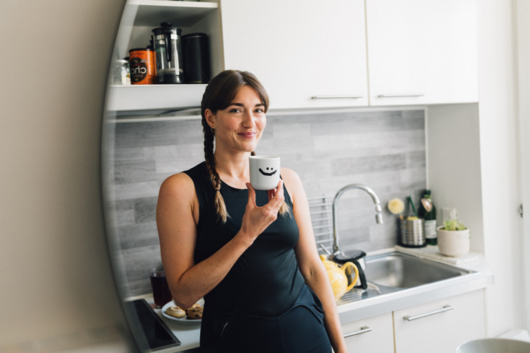 Mosolygó lány konyhában mosolygó bögrét tart