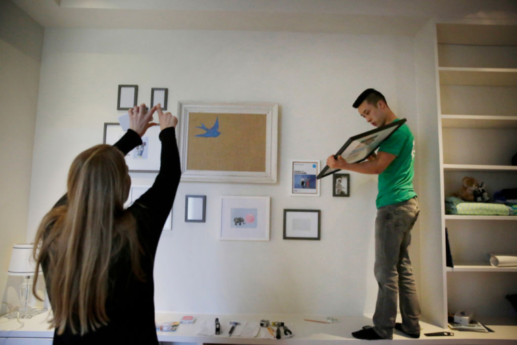 képeket falra erősítő nő és férfi