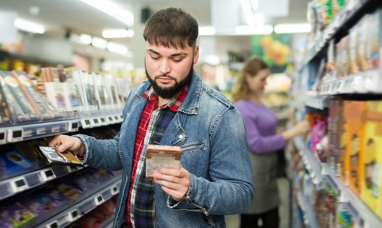 Egy fiatal férfi csokoládét tart a kezében a boltban.