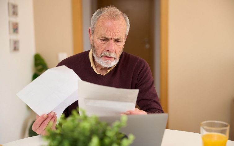 Senior man carefully reviewing documents at home prices and financial crisis Startlap Vásárlás Egy idős férfi egy levelet olvas.