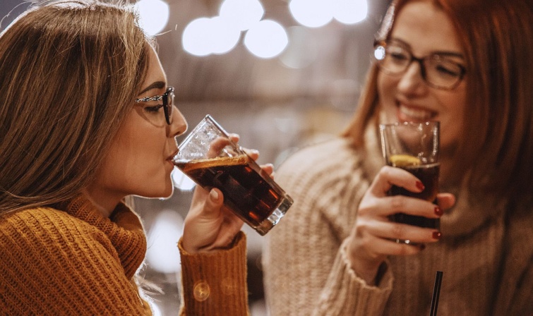 Két szemüveges nő pohárból kólát iszik