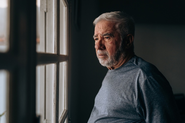 Nyugdíjas férfi az ablak előtt 