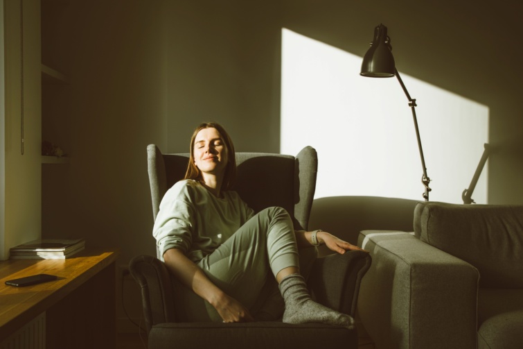 Mosolygó nő fotelben ül a fényben.