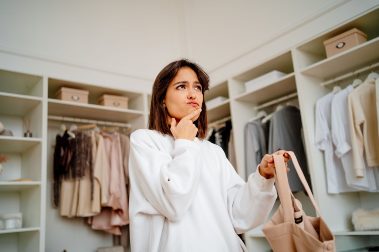 Ruhásszekrény előtt gondolkodó nő.