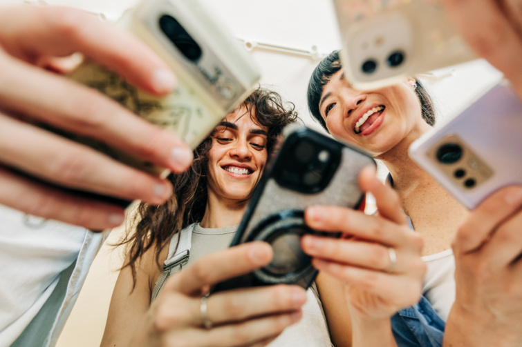 Fiatalok mosolyogva nézik a telefonjukat