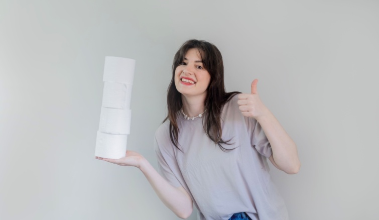 Mosolygó nő vécépapírgurigákat tart a kezében.