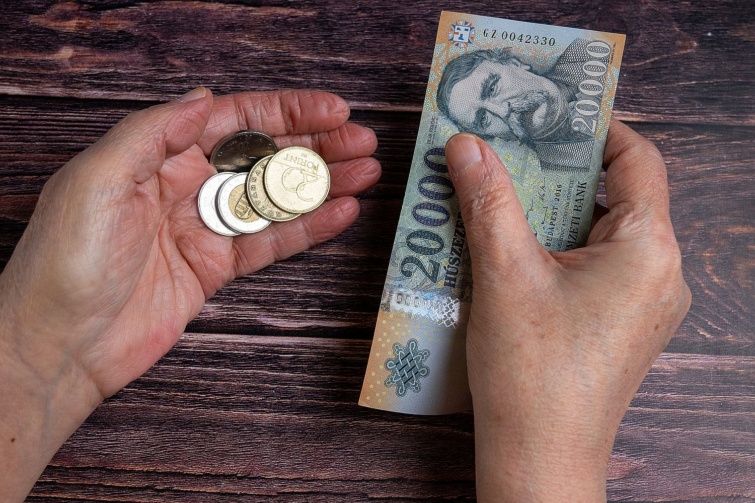 Forintérmék és egy 20 ezer forintos bankjegy egy kézben.