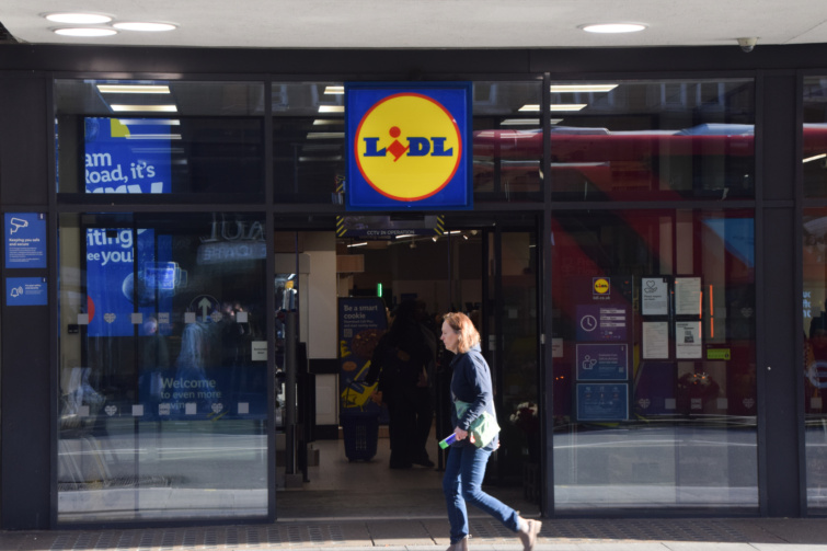 A Lidl egyik üzlete előtt sétál egy nő