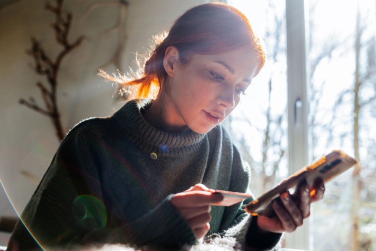 online fizetes Startlap Vásárlás Nő telefonnal és bankkártyával a kezében.