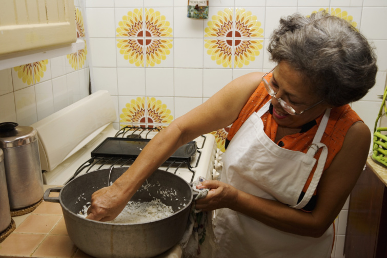 Idősebb nő otthoni konyhájában rizst főz