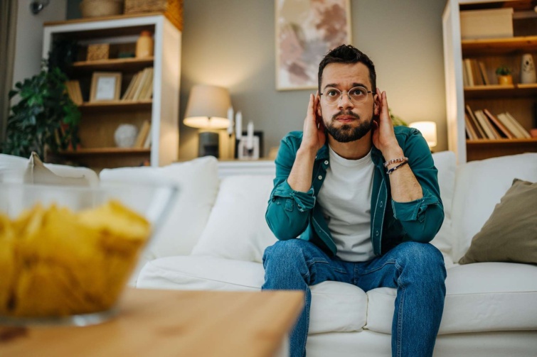 tv néző férfi a kezeit a fülei elé tartja