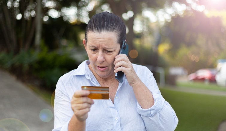 Online Scams Security Startlap Vásárlás Idős, telefonáló nő aggódva nézi a bankkártyáját.