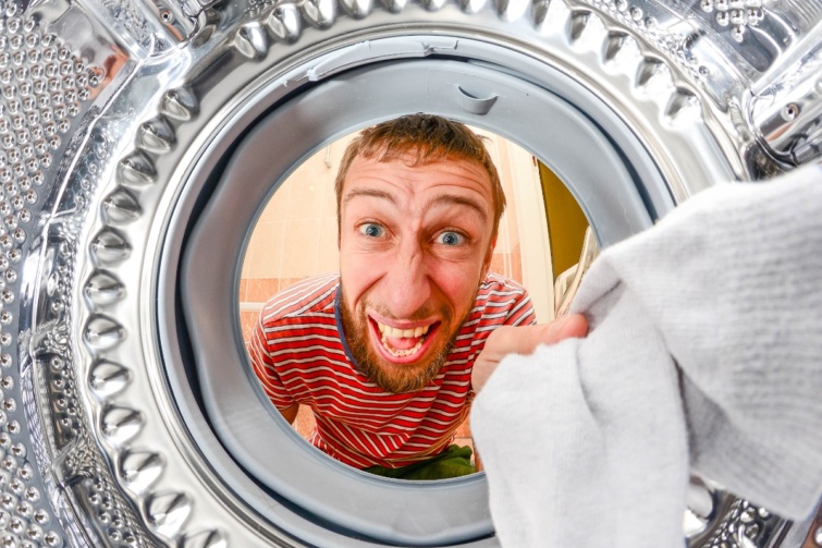 Man Doing Laundry Reaching Inside Washing Machine Startlap Vásárlás Egy férfi dühösen benéz a mosógép ajtaján, miközben egy fehér ruhát fog