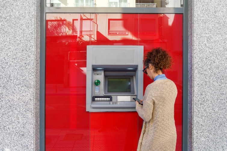 Fiatal nő készpénzt vesz fel bankautomatából