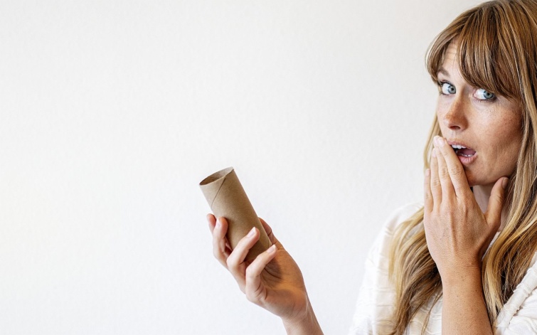 Woman holding an empty toilet paper roll during coronavirus pandemic Startlap Vásárlás Egy meglepődött nő üres wc-papírgurigát tart a kezében.