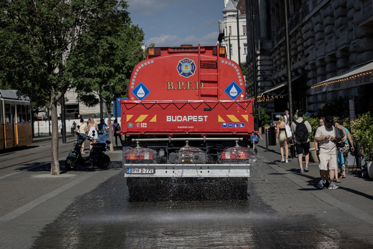 Piros locsolóautó önti le vízzel a betont a budapesti belvárosban