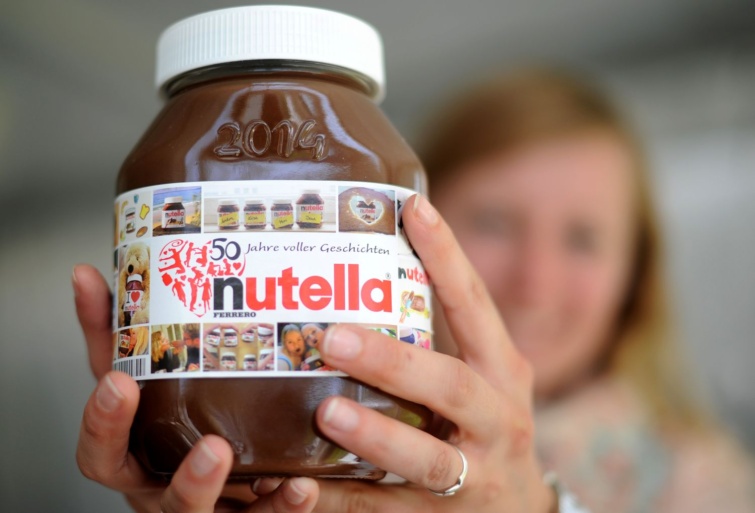 Közelről mutatja egy hölgy a Nutellás üveget, melyen szerepel egy különleges logó is. A Nutella 2014-ben lett 5 éves, erre az alkalomra pedig külön logót kapott a népszerű édesség.