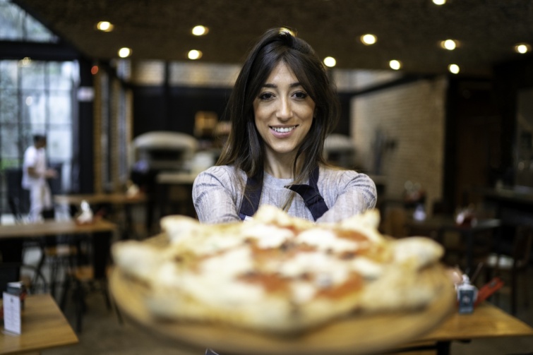 Egy fiatal nő pizzát szolgál fel