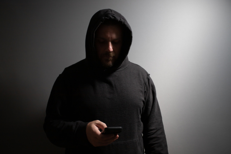 csalo telefon Startlap Vásárlás kapucnis férfi telefont tarts a sötétben
