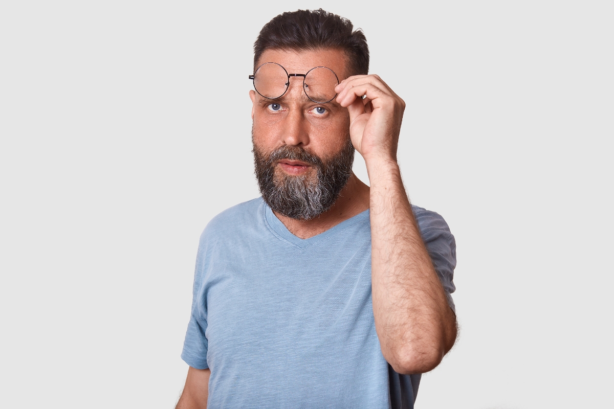 Egy szakállas férfi a szemüvegét igazítja