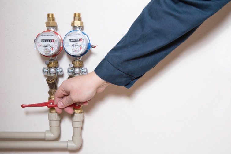 A man turns off a hot water faucet Planned shutdown of hot water and repair of the heating main Copy space for text Startlap Vásárlás Két vízóra egymás mellett