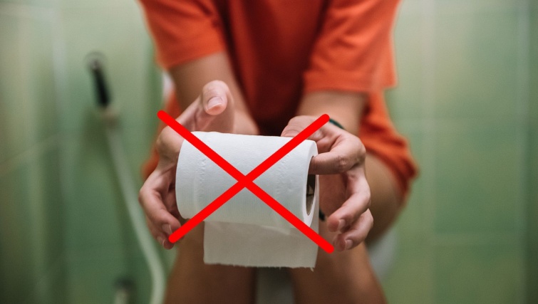 Woman sitting on toilet holding toilet paper roll Startlap Vásárlás Nő ül a wc-n, kezében piros x-szel áthúzott wc-papír