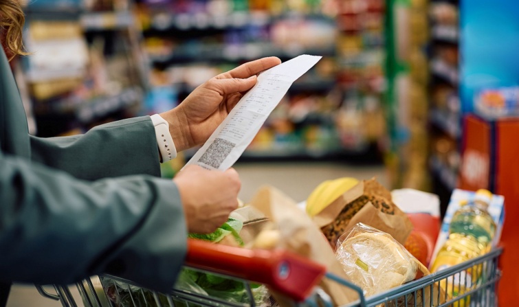 Close up of woman checking the bill after buying groceries in supermarket Startlap Vásárlás Egy nő a boltban a nyugtát tanulmányozza az élelmiszerrel teli bevásárlóocsira támaszkodva.